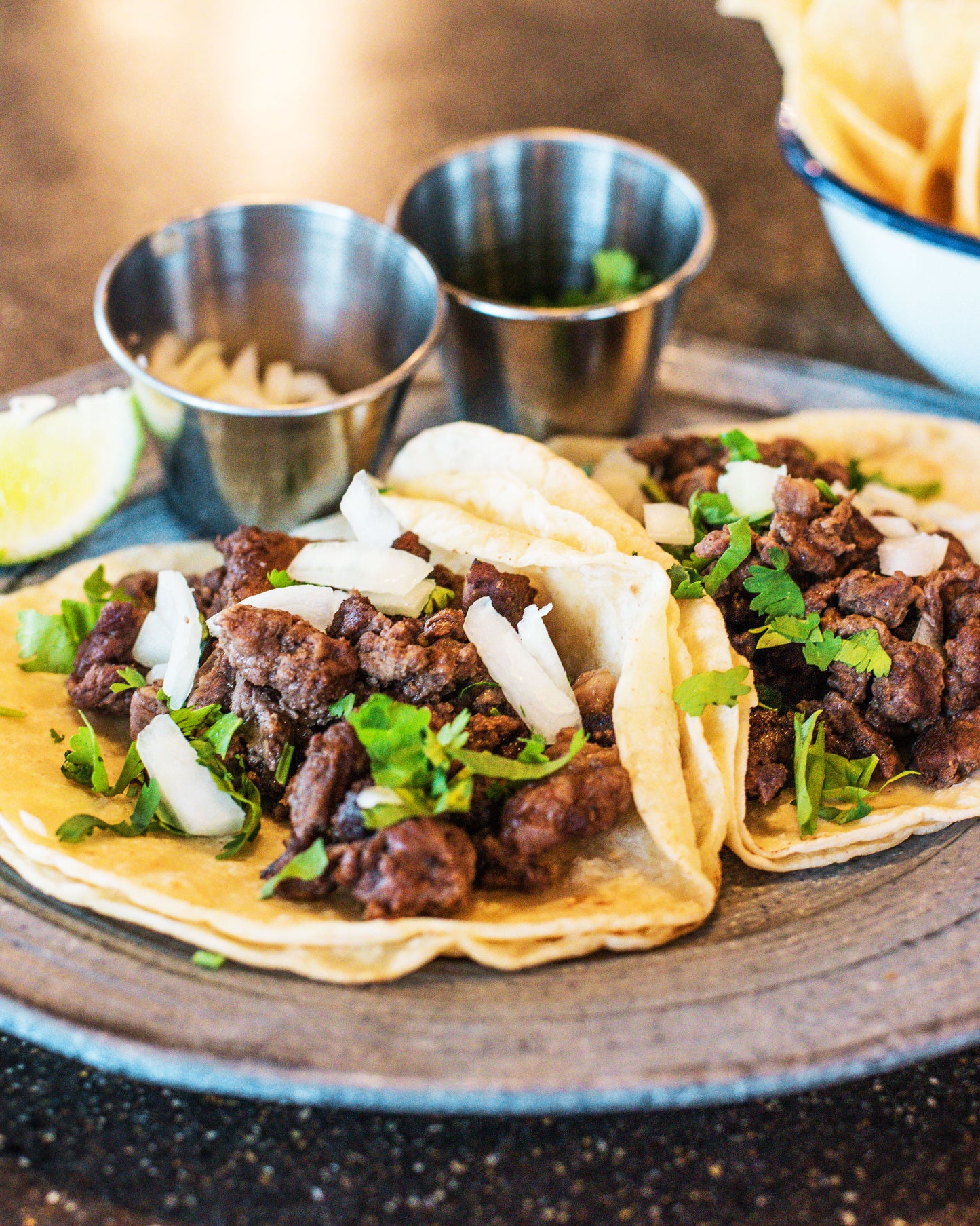 Plate of tacos with chips and salsa on the side.