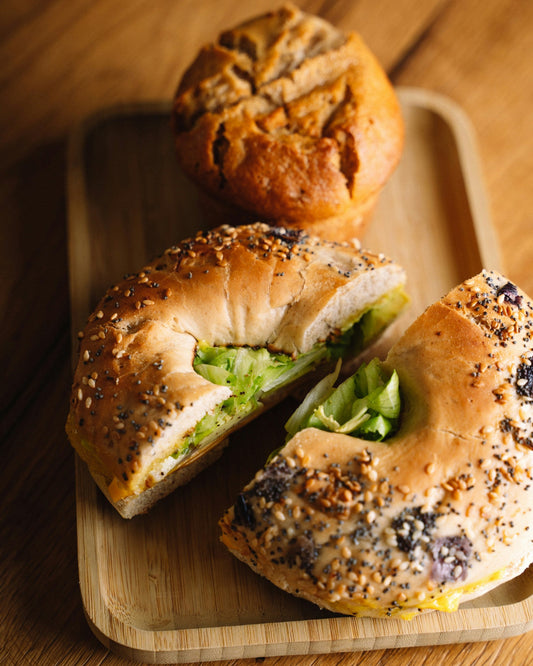 Bagel sandwich and muffin on wooden rectangle pate